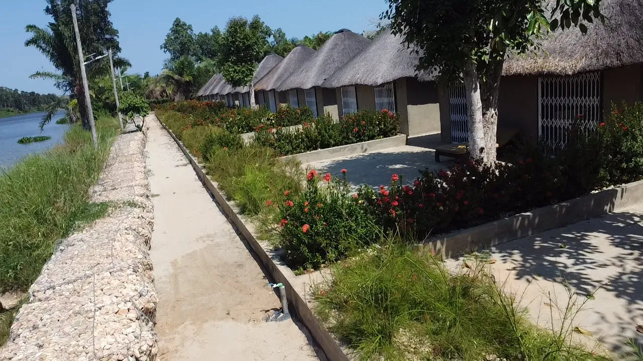 Stone-lined riverside pathway beside the resort's thatched chalets